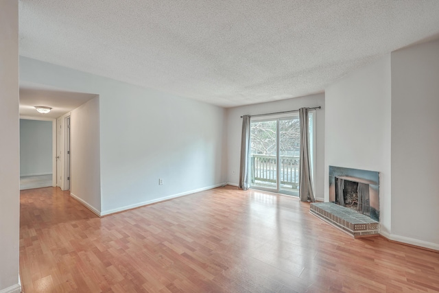 unfurnished living room featuring a fireplace, light wood-type flooring, and a textured ceiling