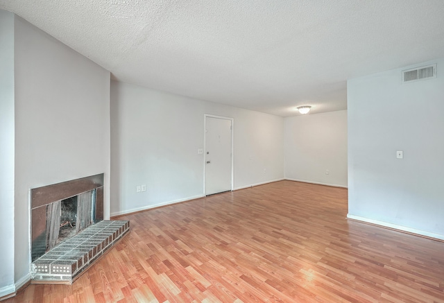 unfurnished living room with a fireplace, light wood-type flooring, and a textured ceiling