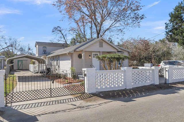 bungalow-style home with a fenced front yard, an outdoor structure, a gate, a detached carport, and a storage unit