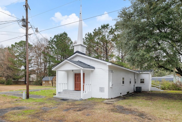 view of front facade featuring central air condition unit, a front yard, and a storage shed