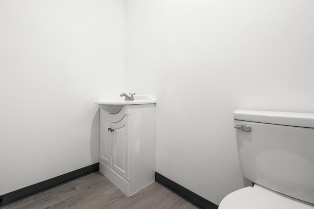 bathroom with hardwood / wood-style floors, vanity, and toilet