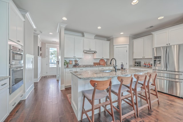 kitchen featuring light stone countertops, appliances with stainless steel finishes, white cabinets, and sink