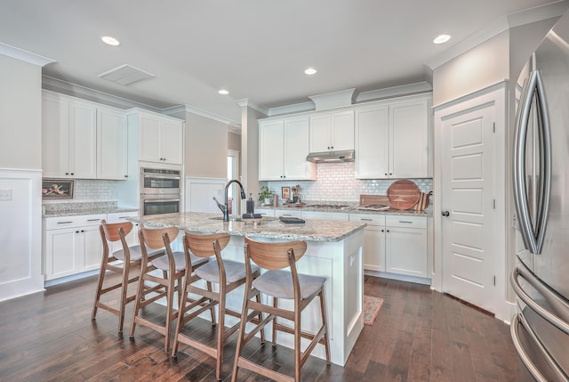 kitchen featuring white cabinets, a kitchen island with sink, and appliances with stainless steel finishes