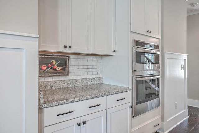 kitchen featuring light stone countertops, white cabinets, double oven, tasteful backsplash, and dark hardwood / wood-style floors