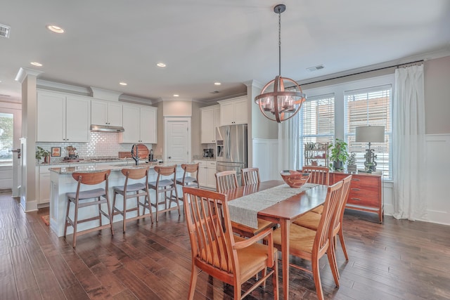 dining room featuring dark hardwood / wood-style floors, sink, a chandelier, and ornamental molding