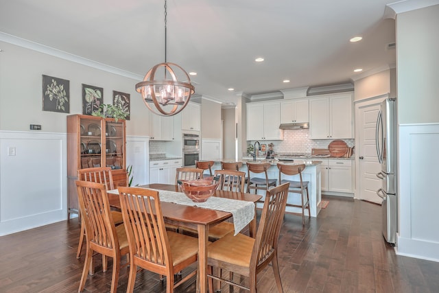 dining room featuring dark wood-type flooring, a chandelier, crown molding, and sink