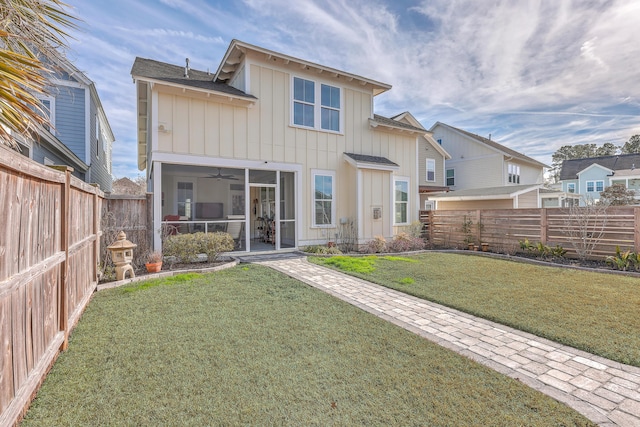 rear view of house featuring ceiling fan, a sunroom, and a yard