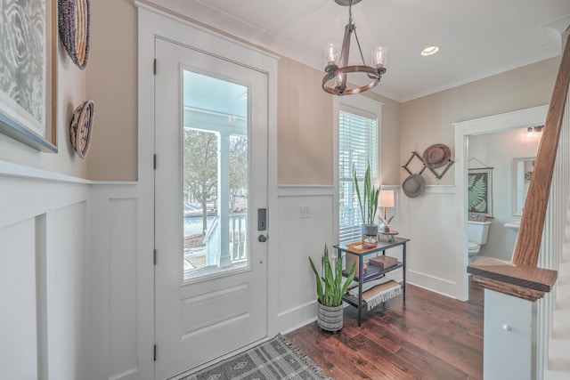 doorway to outside with dark hardwood / wood-style flooring, crown molding, and a notable chandelier