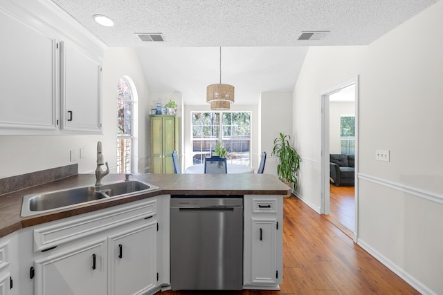 kitchen featuring vaulted ceiling, a peninsula, stainless steel dishwasher, and a sink