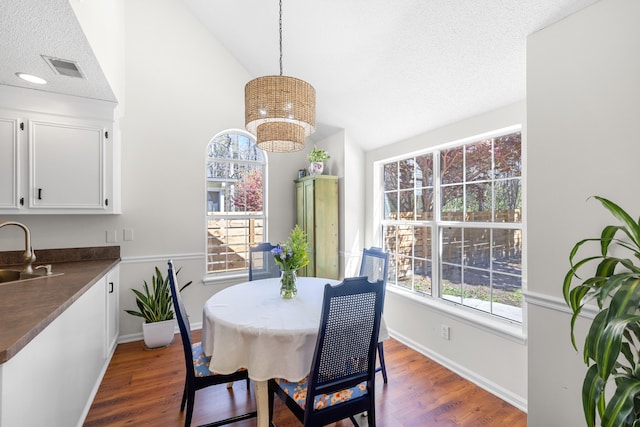 dining space with dark wood-style flooring, vaulted ceiling, and baseboards