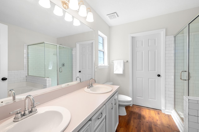 bathroom featuring a stall shower, visible vents, a sink, and wood finished floors