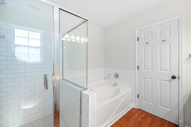 full bath featuring a garden tub, a shower stall, and wood finished floors