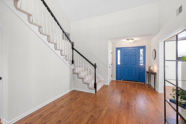 foyer with baseboards, stairs, visible vents, and hardwood / wood-style floors