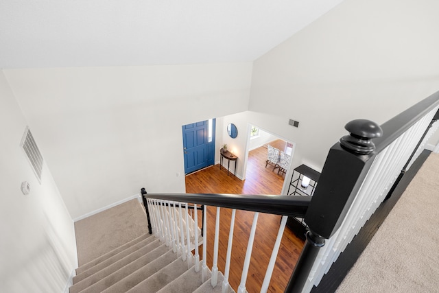 staircase with high vaulted ceiling, carpet floors, visible vents, and baseboards