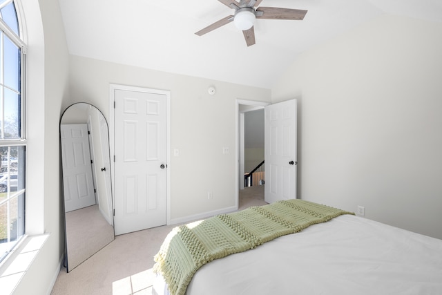 bedroom with light carpet, vaulted ceiling, baseboards, and ceiling fan