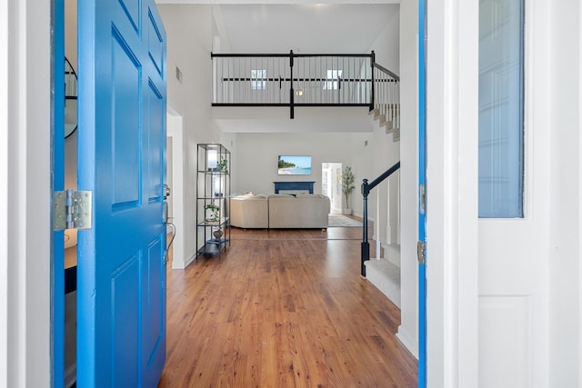 foyer with a fireplace, stairway, a high ceiling, wood finished floors, and baseboards