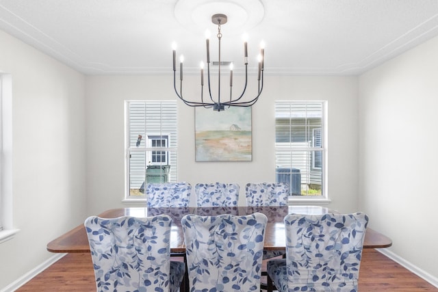 dining area featuring a notable chandelier, baseboards, and wood finished floors