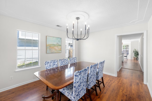 dining space featuring a textured ceiling, wood finished floors, visible vents, baseboards, and an inviting chandelier