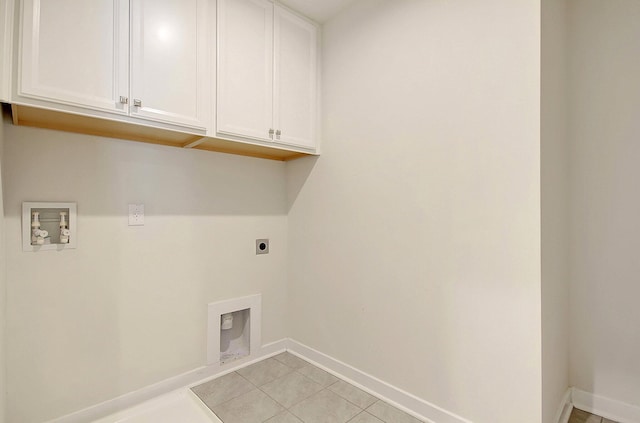 laundry area featuring electric dryer hookup, hookup for a washing machine, light tile patterned floors, and cabinets