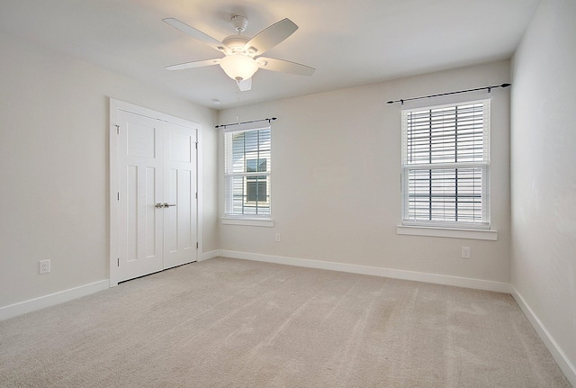 unfurnished bedroom featuring light carpet, a closet, and ceiling fan