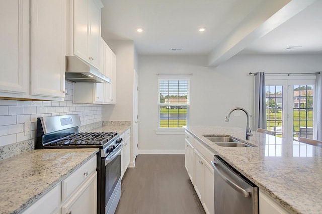 kitchen featuring light stone counters, stainless steel appliances, white cabinetry, and sink