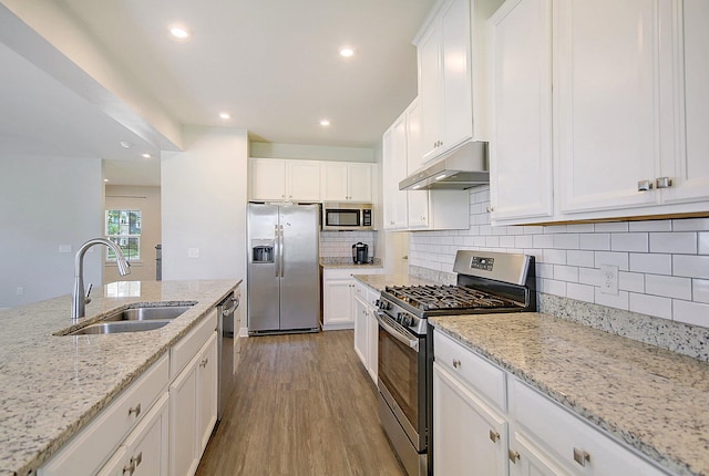 kitchen featuring sink, white cabinetry, light stone counters, wood-type flooring, and stainless steel appliances