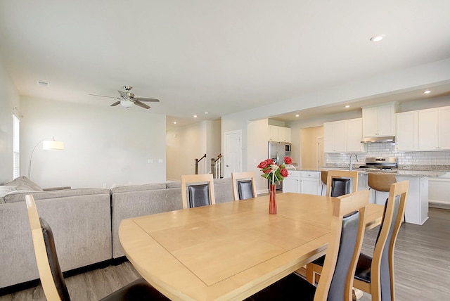 dining area with hardwood / wood-style floors, ceiling fan, and sink