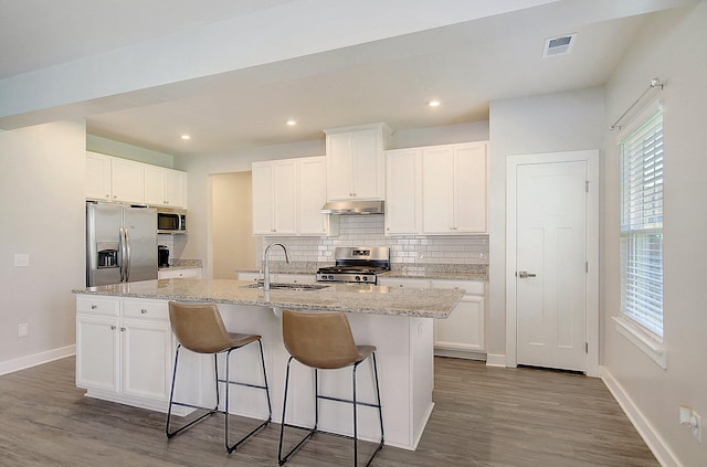 kitchen featuring white cabinetry, sink, dark wood-type flooring, stainless steel appliances, and a center island with sink