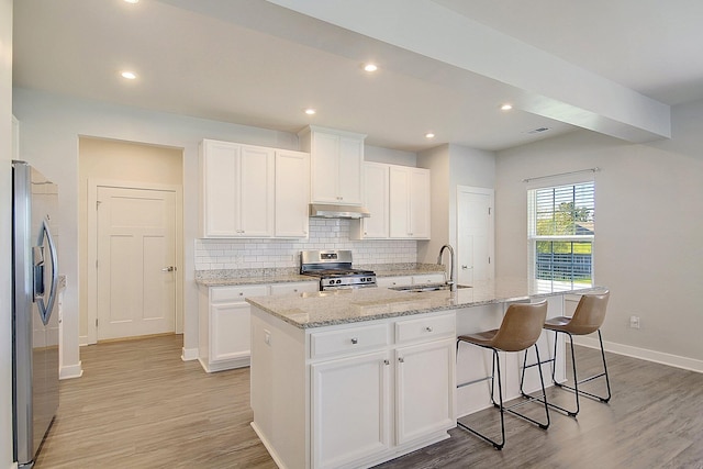 kitchen featuring white cabinets, appliances with stainless steel finishes, a center island with sink, and sink