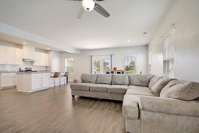 living room with ceiling fan, light wood-type flooring, and sink