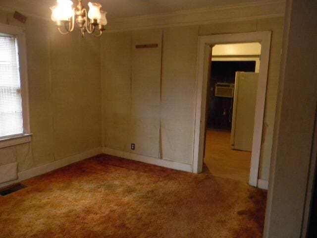 unfurnished room with light carpet and a notable chandelier