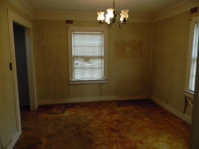 unfurnished room featuring a chandelier