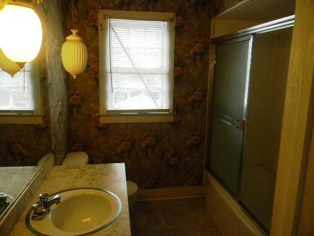 full bathroom featuring vanity, enclosed tub / shower combo, and toilet