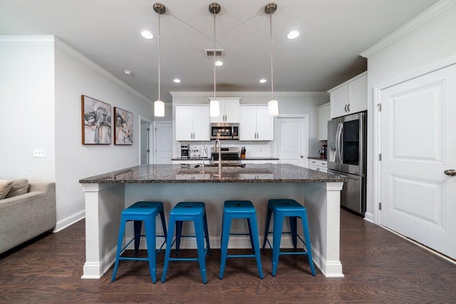 1630 Mermentau St, Mount Pleasant, SC 29466 - kitchen featuring appliances with stainless steel finishes, a kitchen breakfast bar, dark stone countertops, white cabinets, and a center island with sink
