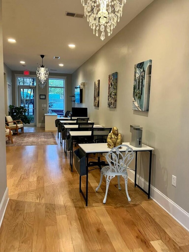 miscellaneous room with an inviting chandelier and light hardwood / wood-style flooring