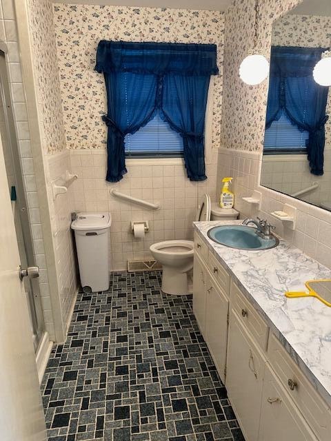 bathroom with vanity, toilet, and tile walls