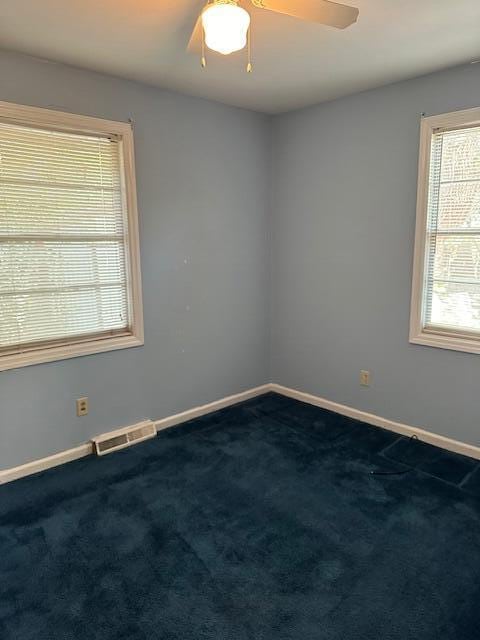 carpeted spare room featuring a healthy amount of sunlight and ceiling fan