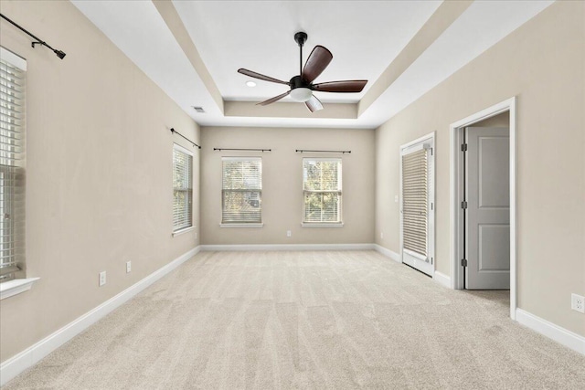 unfurnished bedroom featuring ceiling fan, light colored carpet, and a raised ceiling