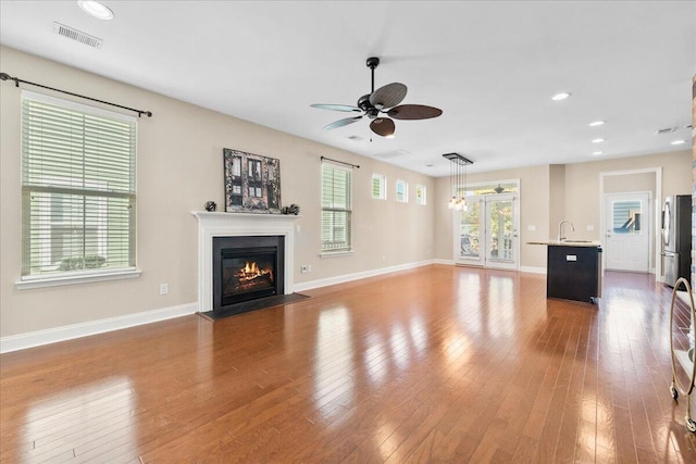 unfurnished living room featuring sink, hardwood / wood-style flooring, and ceiling fan