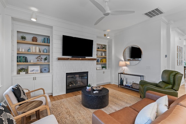 1530 Willtown St, Daniel Island, SC 29492 - living room with ornamental molding, light wood-style flooring, ceiling fan, built in shelves, and a fireplace