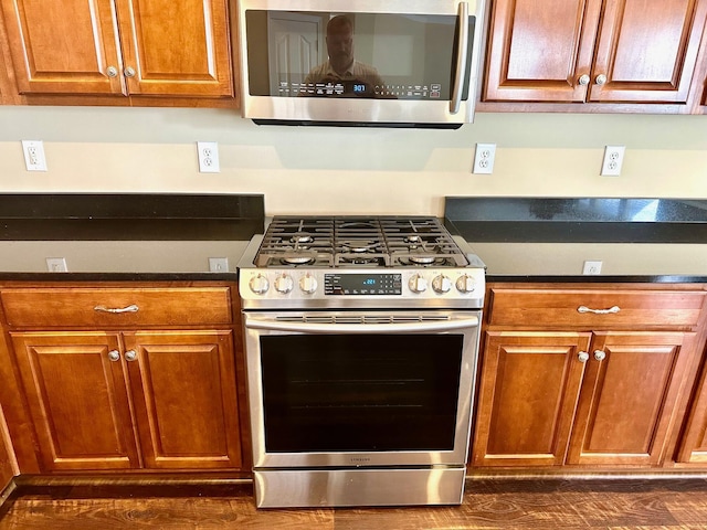 kitchen with appliances with stainless steel finishes, dark countertops, and brown cabinetry