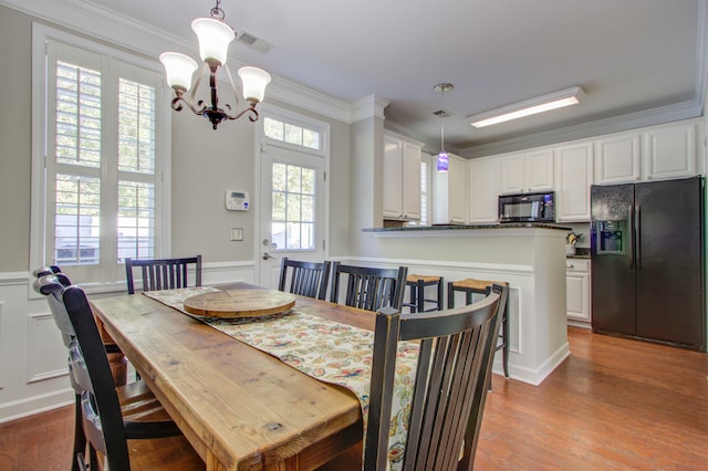 dining space featuring light hardwood / wood-style floors, crown molding, and a chandelier