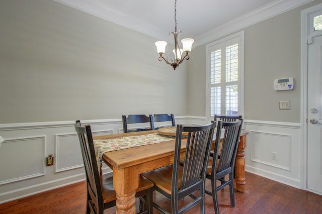 dining area with ornamental molding, dark wood-type flooring, and an inviting chandelier