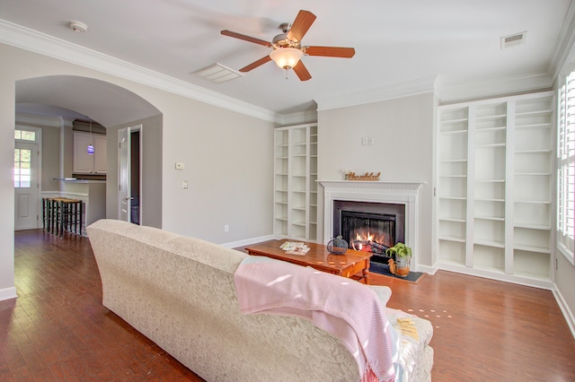 living room with dark hardwood / wood-style flooring, ceiling fan, and ornamental molding