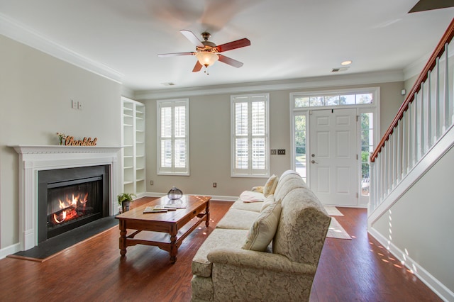 living room featuring built in shelves, ceiling fan, wood-type flooring, and ornamental molding