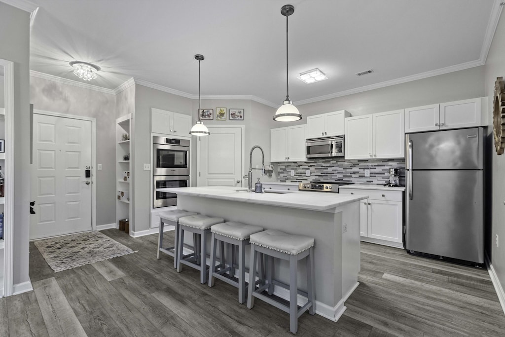 kitchen with white cabinets, appliances with stainless steel finishes, a breakfast bar area, and dark wood-type flooring