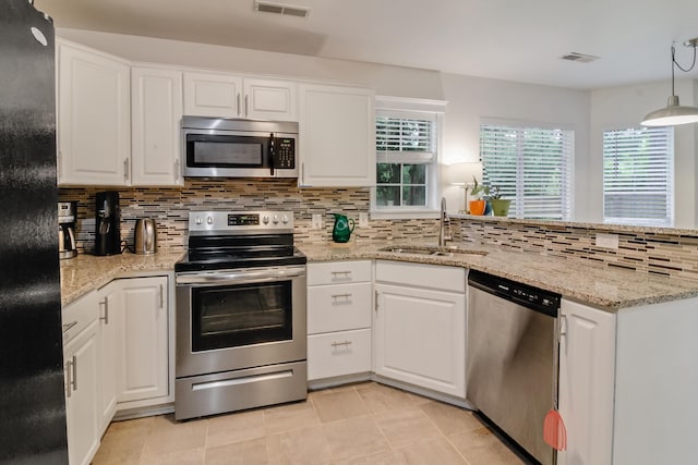 kitchen with stainless steel appliances, a sink, tasteful backsplash, and white cabinetry