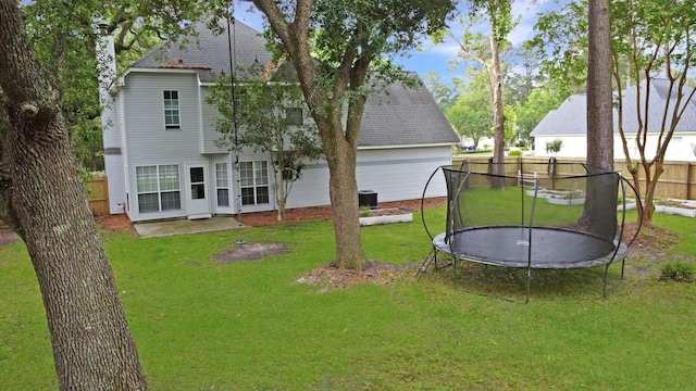 rear view of house featuring a trampoline, a shingled roof, and central AC unit