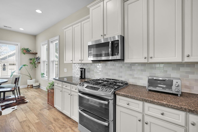 kitchen with stainless steel appliances, light wood-type flooring, visible vents, and decorative backsplash