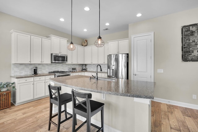 kitchen featuring a sink, visible vents, appliances with stainless steel finishes, light wood-type flooring, and backsplash